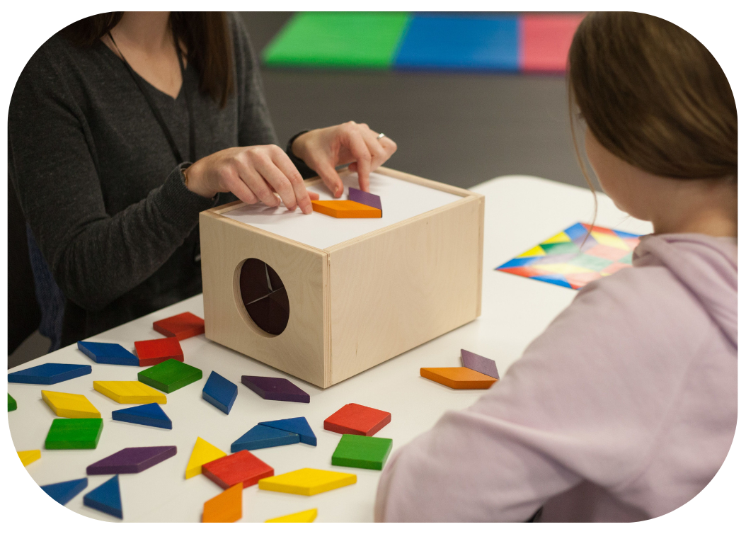 Dr. Tedra Kindopp using coloured wood shapes to perform a functional vision test with a young girl.
